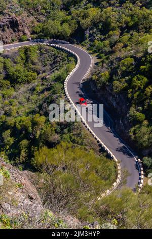 Luftaufnahme eines roten Autos auf einer kurvenreichen Straße in der Masca-Schlucht in der Berggemeinde im Norden von Teneriffa, Kanarische Inseln, Spanien Stockfoto