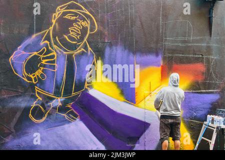 Straßenkünstler arbeitet an einem Wandgemälde an der berühmten Hosier Lane im Zentrum von Melbourne, Victoria, Australien. Stockfoto