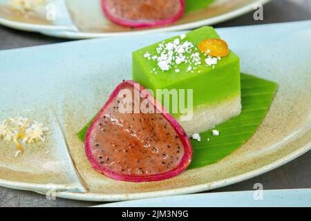 Teller mit Green Mochi Dessert mit Kokosmilch und Scheibe Drachenfrucht mit Korn aus dem Fokus lassen Stockfoto