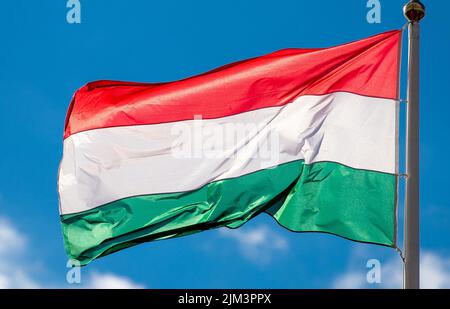 Eine Nahaufnahme der im Wind flatternden ungarischen Flagge, realistisch Stockfoto