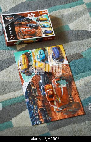 Die Mattel Cruz Ramirez und Lightning McQueen auf einem Trefl Disney Pixar Cars Puzzle neben Box. Stockfoto