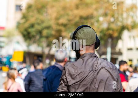 Barcelona, Spanien - 8. April 2022: Nicht erkennbarer Hintermann, der im gotischen Viertel von Barcelona (Spanien) Musik mit Kopfhörern hört. Stockfoto