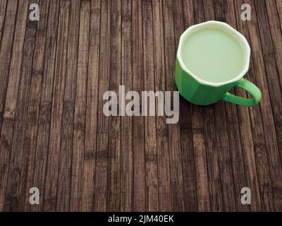 Becher Matcha Latte aus Mandelmilch auf einem Holztisch Stockfoto