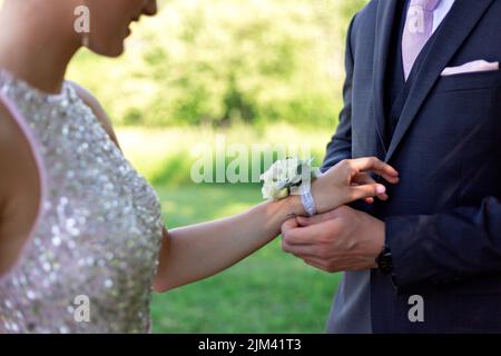 Nahaufnahme eines Bräutigams, der während der Trauung an einem sonnigen Tag ein Armband auf die Hand der Braut legt Stockfoto