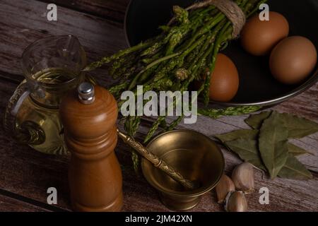 Bund wilder Spargel in einer Pfanne mit Zutaten für ein Omelett Eier, Knoblauch, Lorbeerblatt und Öl zu machen Stockfoto