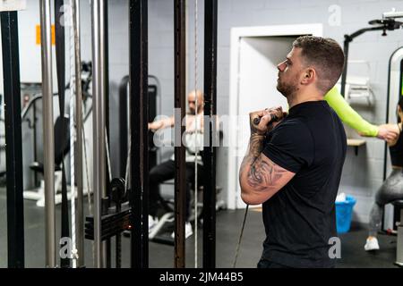 Kaukasischer muskulöser Mann, der Bizeps-Übungen im Fitnessstudio macht. Lifestyle, Workout-Konzept, Copy Space Stockfoto