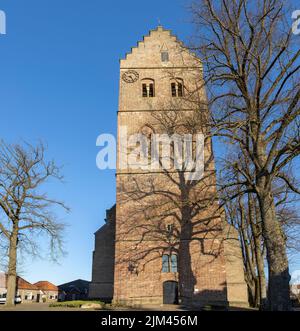 Hoher Kirchturm von Christophorus kerk in der Stadt Geesteren von unten gesehen mit kargen Winterzweigen Stockfoto