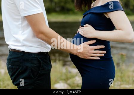 Ein junger Mann, der den Bauch ihrer 38-wöchigen Schwangeren hielt Stockfoto