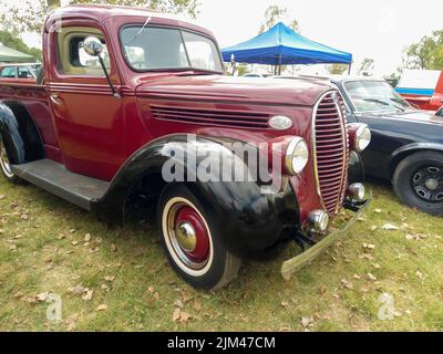 Alte rot-schwarze LKW-Pickup Ford 85 V8 1938 - 1939 auf dem Land. Naturrasen und Bäume. Oldtimer-Show. Stockfoto