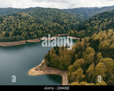 Eine Luftaufnahme des Sees Vidraru, umgeben von üppigen Wäldern in der Grafschaft Arges, Rumänien Stockfoto