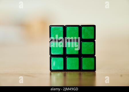 Ein gelöster Rubik-Würfel, der auf einer glänzenden Holzoberfläche steht Stockfoto