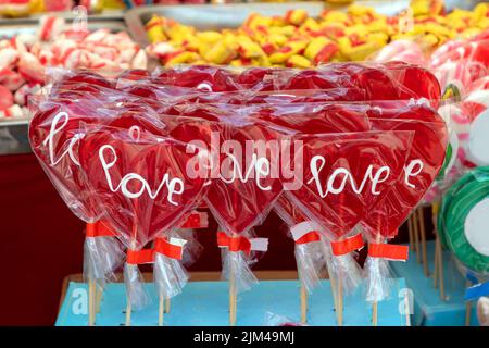 Rote herzförmige Lutscher mit Liebes-Text-Zeichen auf dem Markt verkauft Stockfoto