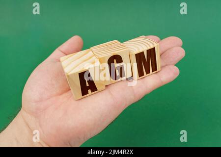 Geschäftskonzept. Auf einem grünen Hintergrund, in den Händen einer Person, Würfel mit der Aufschrift - AGM Stockfoto