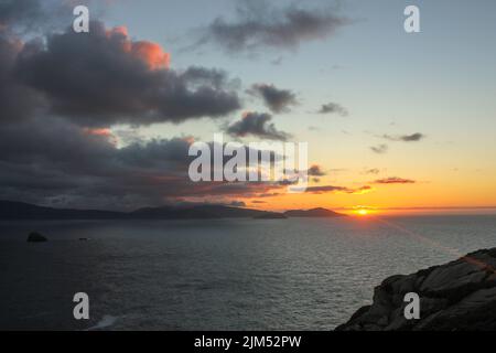 Die Sonne, die im Meer sinkt, lässt ihre letzten Strahlen für uns zum Genießen zurück Stockfoto