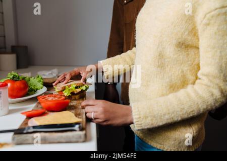 Schwarzer bärtiger Mann, der mit seiner Tochter zu Hause Sandwiches zubereitet Stockfoto