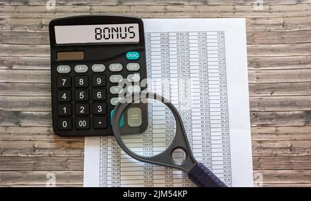 WORTBONUS auf der Anzeige eines Rechners über Finanzdokumente. Stockfoto