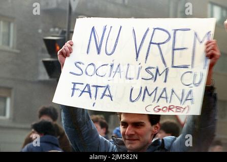 Bukarest, Rumänien, Januar 1990. Kundgebung auf dem Universitätsplatz nach der rumänischen Revolution von 1989. Die Menschen versammelten sich täglich, um gegen die ehemaligen kommunistischen Beamten zu protestieren, die nach der Revolution die Macht ergriffen hatten. Junger Mann mit einem Schild, auf dem steht: „Wir wollen keinen Sozialismus mit menschlichem Antlitz“. Stockfoto