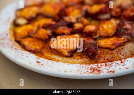 Im spanischen Restaurant werden leckere Meeresfrüchte, gegrillter Tintenfisch im galizischen Stil mit rotem Paprika und Kartoffeln serviert Stockfoto