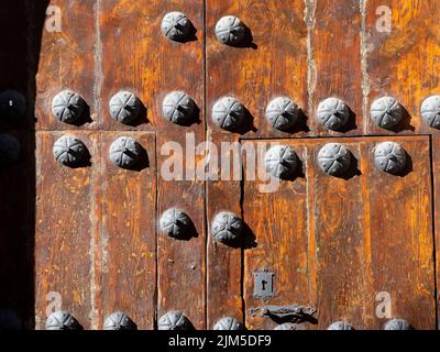 Eine Nahaufnahme einer alten mittelalterlichen Holztür mit Metalldekorationen. Stockfoto