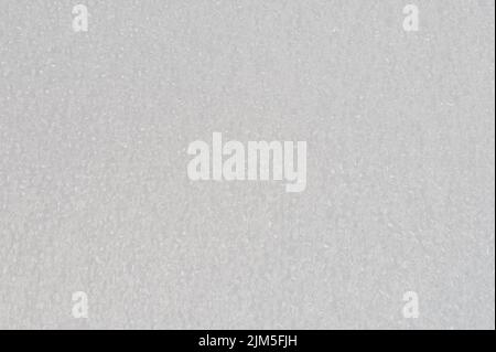 Makro-Nahaufnahme mit weißem Weichschaum-Hintergrund. Muster aus Polyesterpartikeln Stockfoto