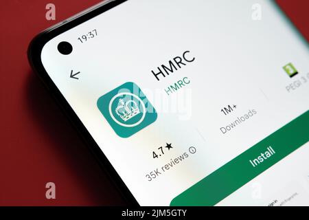 HMRC-App im Google Play Store auf dem Smartphone-Bildschirm auf rotem Hintergrund angezeigt. Nahaufnahme mit selektivem Fokus. Stafford, Großbritannien, A Stockfoto