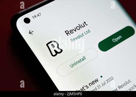 revolut App im Google Play Store auf dem Smartphone-Bildschirm auf rotem Hintergrund angezeigt. Nahaufnahme mit selektivem Fokus. Stafford, Großbritannien Stockfoto