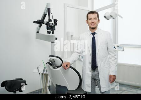 Porträt eines glücklichen männlichen Zahnarztes mit Laborkittel in der weißen Zahnklinik Stockfoto