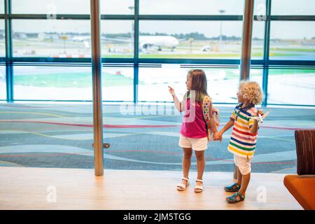 Kinder am Flughafen. Kinder schauen auf das Flugzeug. Reisen und Fliegen mit Kind. Familie am Abflugsteig. Urlaub und Reisen mit kleinen Kindern. Stockfoto