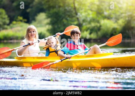 Kind mit Paddel im Kajak. Sommercamp für Kinder. Kajakfahren und Kanufahren mit der Familie. Kinder im Kanu. Familie auf Kajakfahrt. Stockfoto