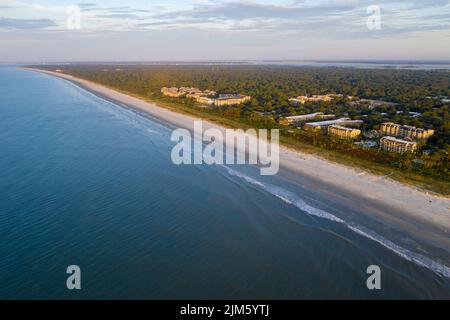 Blick aus der Vogelperspektive auf den Coligny Beach auf Hilton Head Island. Blick auf das Meer bei Sonnenuntergang mit Bäumen und Hotels im Vordergrund Stockfoto