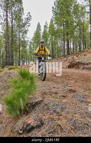 Ein Radsportler in einer gelben Jacke, der in La Palma, Kanarische Inseln, die Landschaft entlang fährt Stockfoto