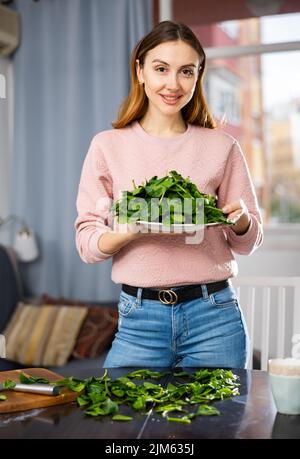 Glückliches Mädchen, das köstlichen Spinatsalat aus der Nähe macht Stockfoto