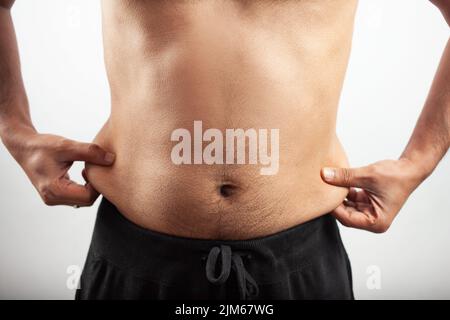 indischer ungesunder Cropped Mann zeigt Seite Bauchfett in isolierten Hintergrund Stockfoto