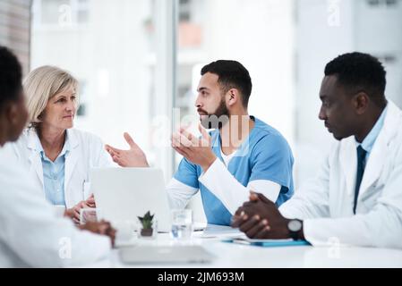 Gemeinsam einen effektiven Behandlungsplan erarbeiten. Eine Gruppe von Ärzten, die sich in einem Sitzungssaal des Krankenhauses treffen. Stockfoto