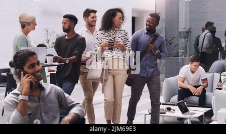 Macher und Macher halten es in Bewegung. Eine Gruppe junger Geschäftsleute, die durch ein Kongresszentrum laufen. Stockfoto