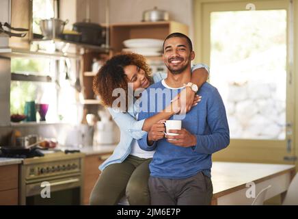 Schwarzes Paar entspannt, trinkt Kaffee und schaut glücklich zusammen in der Küche am Morgen zu Hause. Porträt einer jungen, fröhlichen und liebevollen Stockfoto