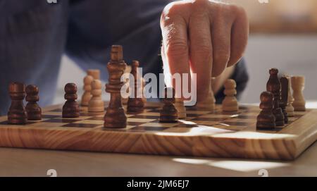 Ich brauchte ein Gehirnspiel. Ein unkennbarer Mann, der allein saß und in der Küche zu Hause Schach spielte. Stockfoto