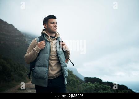 Irgendwann im Leben wird die Schönheit der Welt genug. Ein junger Mann, der durch die Berge wandert. Stockfoto