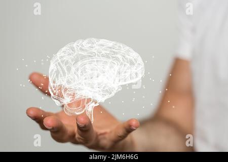 Eine verschwommene männliche Hand, die ein 3D menschliches Denkkonzept der Künstlichen Intelligenz auf einem grauen Hintergrund hält Stockfoto