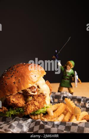 Ein vertikaler Schuss eines knusprigen Hähnchenburger mit lockigen pommes Frites Stockfoto