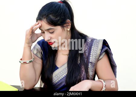 Eine traditionelle indische Frau mit Kopfschmerzen, die ihre Hände an den Kopf hält Stockfoto