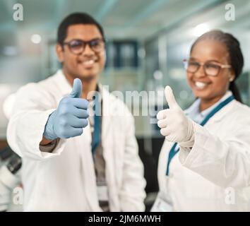 Unser Experiment war ein großer Erfolg. Zwei Wissenschaftler zeigten in einem Labor Daumen nach oben. Stockfoto