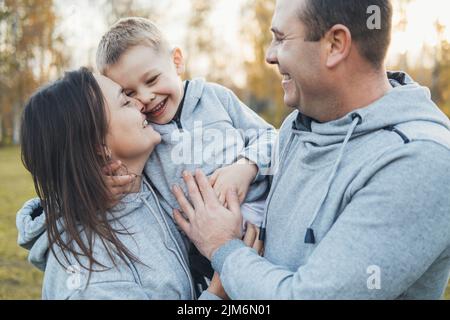 Porträt einer kaukasischen Eltern, die Zuneigung zeigen, indem sie ihren Sohn umarmen und küssen. Nahaufnahme im Hochformat. Glückliche Familie, Kindheit. Stockfoto