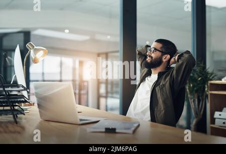 Gönnen Sie sich eine Verschnaufpause, und kehren Sie dann zurück in den Alltag. Ein junger Geschäftsmann, der spät in der Nacht in einem modernen Büro arbeitet. Stockfoto