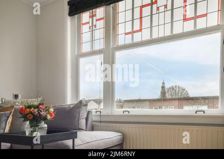 Quadratischer Tisch auf einer Matte in der Nähe von Couch und TV im stilvollen Wohnzimmer der modernen Wohnung platziert Stockfoto