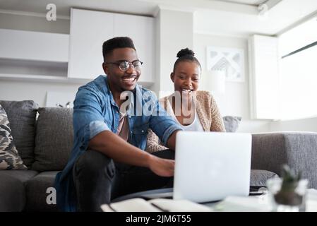 Die Budgetierung ist für sie zu einem Kinderspiel geworden. Ein junges Paar, das zu Hause einen Laptop benutzt. Stockfoto