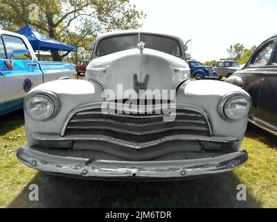 Altes rotes, unlackiertes rostiges Chevrolet Chevy Fleetmaster Sportcoupé 1946 von GM auf dem Rasen geparkt. Vorderansicht. Grill. Oldtimer-Show. Stockfoto