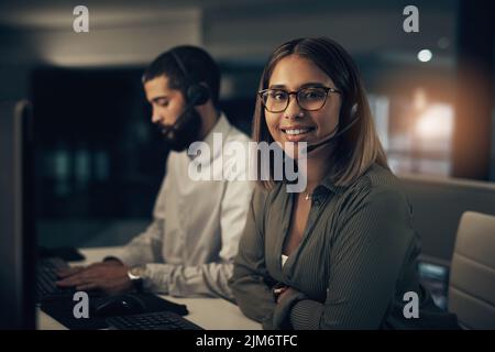 Die Spätschicht ist einfach ein Teil der Arbeit. Porträt eines Callcenter-Agenten, der nachts neben einem Kollegen in einem Büro arbeitet. Stockfoto