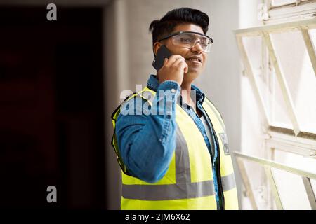 Ich brauche Ihre Hilfe bei diesem Projekt. Ein Ingenieur spricht auf seinem Handy, während er auf einer Baustelle ist. Stockfoto