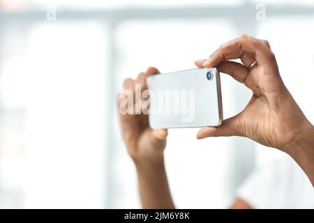 Die intelligenteste Virtual Viewing App auf dem Markt. Eine unkenntliche Frau fotografiert mit einem Smartphone das Innere eines Hauses. Stockfoto